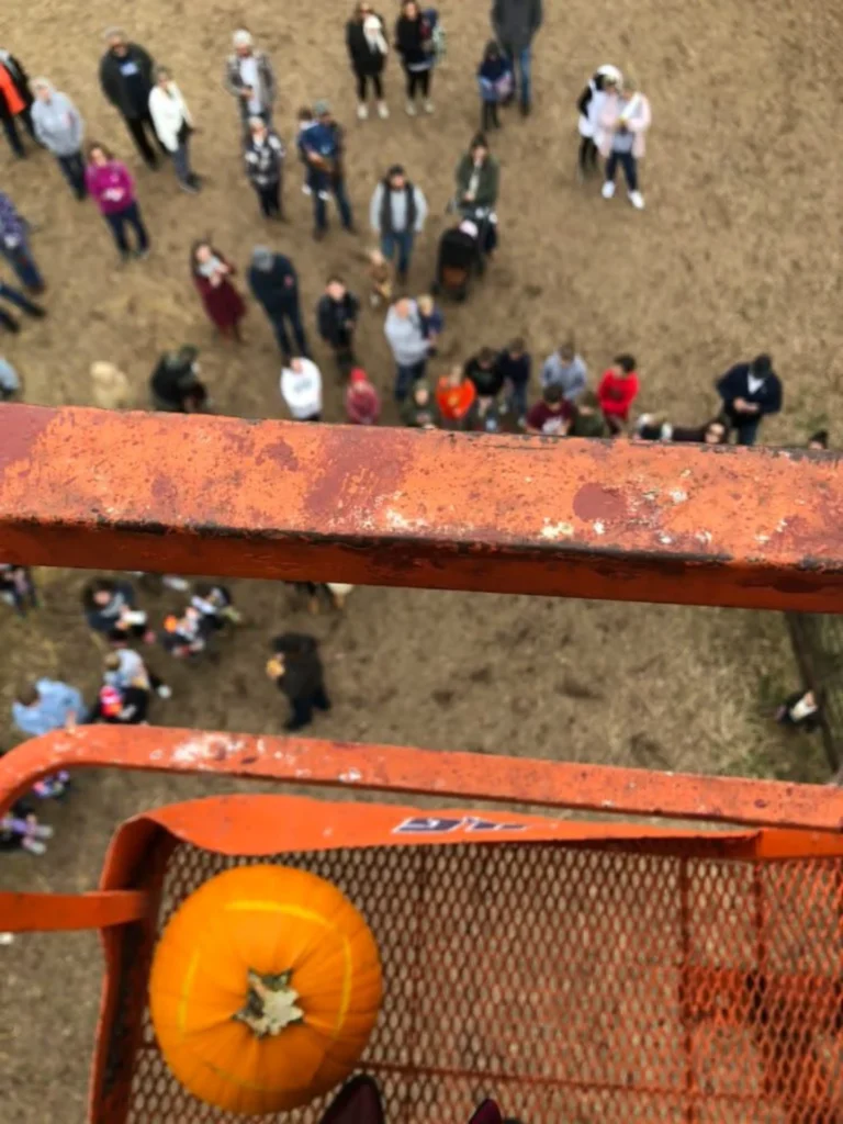 Orange pumpkin on high platform overlooking a crowd below