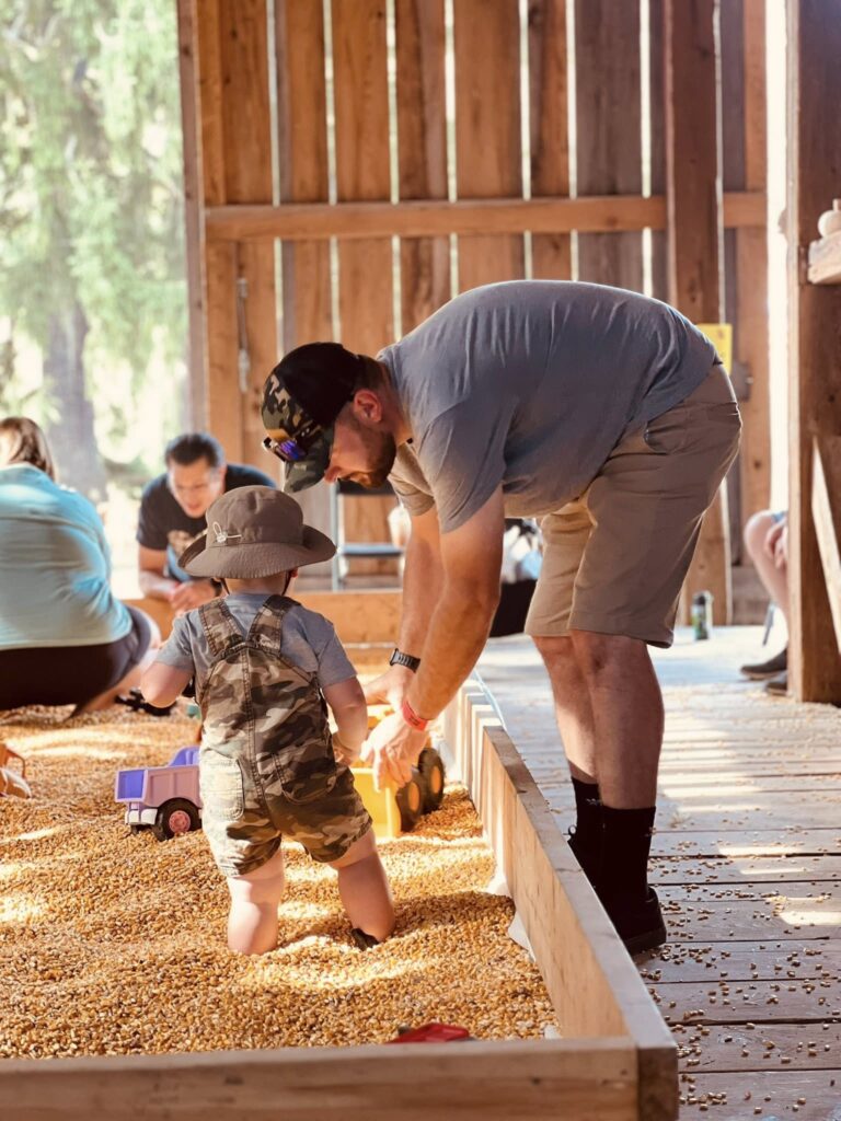 Child exploring grain bin with adult at rustic family farm barn activity