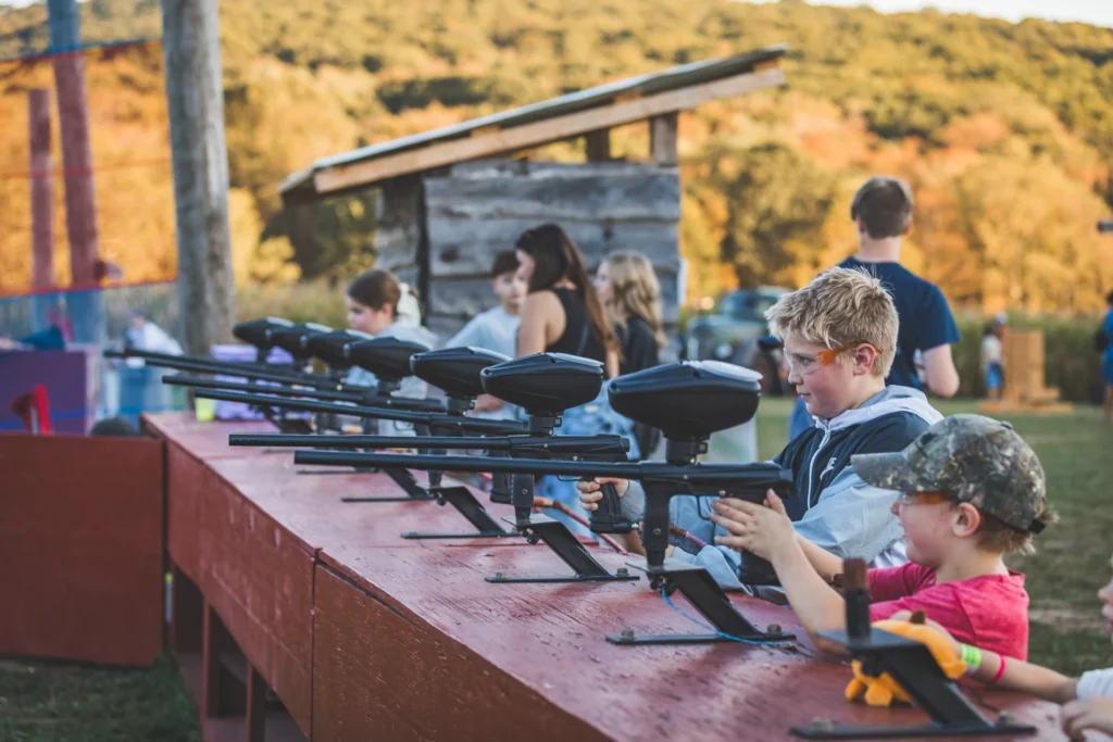 Children practicing at an outdoor shooting range with marker guns on a sunny day.